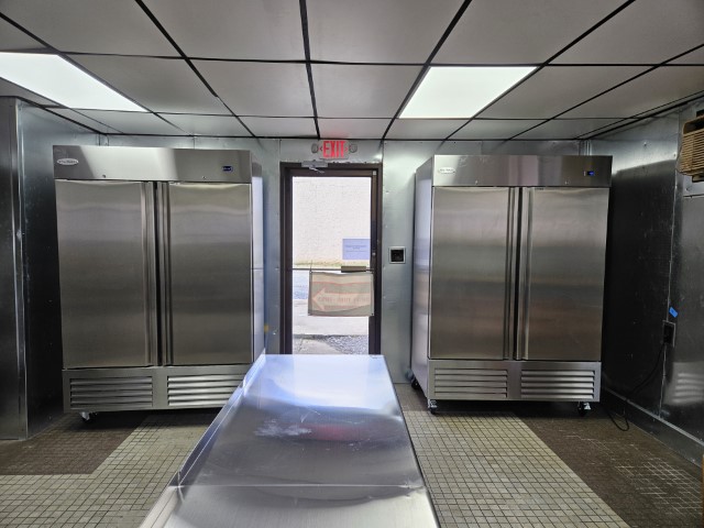 The catering kitchen's large freezer, refrigerator, and one of its entrances.