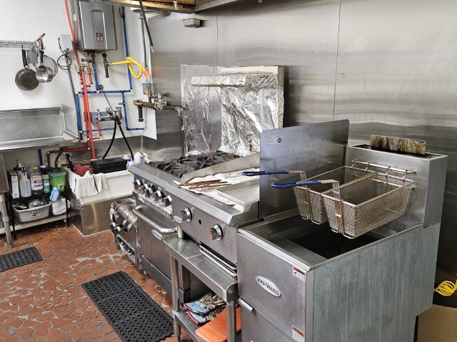 A side view image of a gas burner, flat-top griddle and deep fryer.